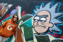 Load image into Gallery viewer, Je Moeder Hoodie Mustard Brown. Mustard brown hoodie with kangeroo pocket and white Je Moeder Mother Earth screenprint. Photo of woman wearing this hoodie .